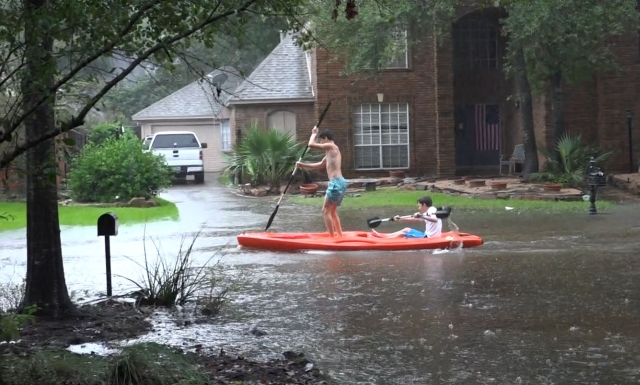 Kids kayaking in front of house during Harvey